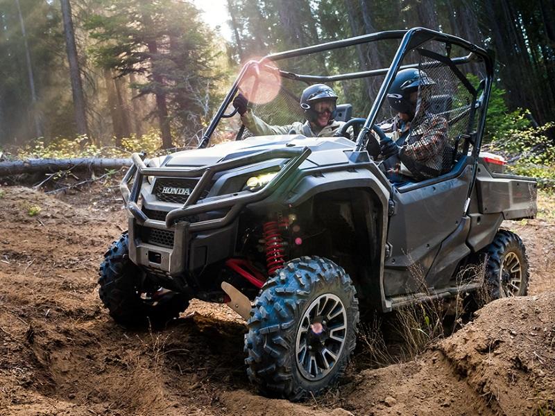 Two people ride in a 2020 Honda® Pioneer through mud